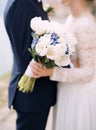 The bride and groom stand hugging and hold a wedding bouquet with white and blue flowers and eucalyptus branches close Royalty Free Stock Photo