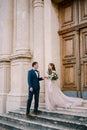 Bride and groom stand on the stone steps of the ancient church at the door Royalty Free Stock Photo
