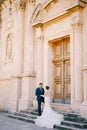 Bride and groom stand on the stone steps in front of the wooden door of the ancient church Royalty Free Stock Photo