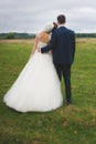 Bride and groom standing back on the green field Royalty Free Stock Photo