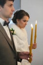 Bride and groom standing at wedding ceremony. Happy stylish wedding couple holding candles with light under golden Royalty Free Stock Photo