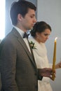 Bride and groom standing at wedding ceremony. Happy stylish wedding couple holding candles with light under golden Royalty Free Stock Photo