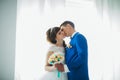 Bride and groom in studio light stand kiss on a white background Royalty Free Stock Photo