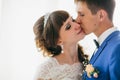 Bride and groom in studio light stand kiss on a white background Royalty Free Stock Photo