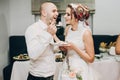 Bride and groom tasting stylish wedding cake at wedding reception in restaurant. Wedding couple plate with slice of cream cake