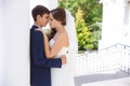 The bride and groom tenderly embrace and hide behind a white column, want to be alone, and escape from their wedding.