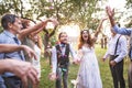 Bride, groom and guests throwing confetti at wedding reception outside. Royalty Free Stock Photo