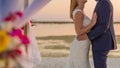 The bride and groom under archway on beach. Calm and romantic white sandy beach for honeymoon destination and love background Royalty Free Stock Photo