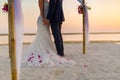 The bride and groom under archway on beach. Calm and romantic white sandy beach for honeymoon destination and love background Royalty Free Stock Photo