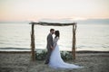 The bride and groom under archway on beach. Sunset, twilight. Royalty Free Stock Photo