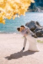 Bride and groom under an autumn tree, with fiery yellow foliage, at the Lago di Braies in Italy. Destination wedding in Royalty Free Stock Photo