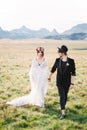 Bride and groom walk down the lawn holding hands Royalty Free Stock Photo