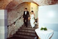 Bride and groom walk downstairs into the restauant holding their Royalty Free Stock Photo