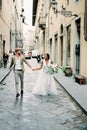 Bride and groom walk hand in hand along an old street in Florence. Italy