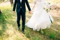 Bride and groom walking together in olive grove and holding hands