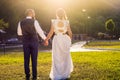 Bride and groom walking towards sunset holding hands Royalty Free Stock Photo