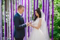 The bride and groom wear each other at a wedding ceremony when rings on a background of multi-colored ribbons, love, marriage, rel