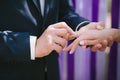 The bride and groom wear each other at a wedding ceremony when rings on a background of multi-colored ribbons, love, marriage, rel