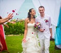 Bride and groom after the wedding ceremony. Guests showered the newlyweds with rose petals on the background of the ocean