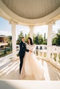 bride and groom in wedding clothes dance in gazebos or rotunda in the park.