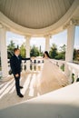 bride and groom in wedding clothes dance in gazebos or rotunda in the park.