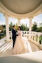 bride and groom in wedding clothes dance in gazebos or rotunda in the park.