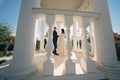 bride and groom in wedding clothes dance in gazebos or rotunda in the park.