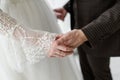 Bride and groom in wedding clothes hold hands with trepidation and love, close-up. Wedding ceremony. Happy couple