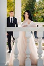 bride and groom in wedding clothes at railing in gazebos or rotunda in the park.