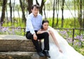 Bride and groom in wedding dress with elegant hairstyle, with white wedding dress Sitting on a rock Royalty Free Stock Photo