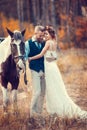 Bride and groom on a wedding walk with a horse in the autumn park, October, vintage style