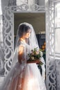 A bride with hairstyle and make up in gorgeous pink wedding dress and a vail with a bouquet of peonies. Royalty Free Stock Photo