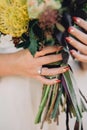 Bride hand with beautiful red manicure and a luxury ring with diamonds is holding a wedding bouquet. Close-up Royalty Free Stock Photo