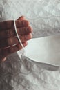 Bride hands holding white medical face mask. Woman in wedding dress during the Coronavirus epidemic. Cancelled or postponed