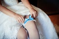 The bride on her wedding day. Morning bride. Close-up of young bride putting on white garter. Royalty Free Stock Photo