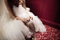 The bride on her wedding day. Morning bride. Close-up of young bride putting on white garter.