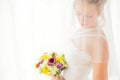 Bride hiding behind veil with flowers in her hands