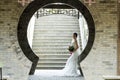 Bride hold bridal bouquet with white wedding dress near a brick arch