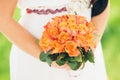 A bride holding a beautiful bouquet of orange roses Royalty Free Stock Photo