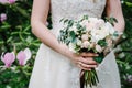 The bride are holding a beautiful wedding bouquet of pastel, pink, white peonies, roses flowers, greenery and decorated with Royalty Free Stock Photo