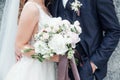 Bride holding a bouquet of flowers in her hand, the groom embracing her