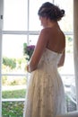 Bride holding bouquet while looking through window at home Royalty Free Stock Photo