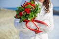 Bride holding a bouquet of red roses and pine cones Royalty Free Stock Photo
