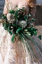 The bride is holding a bouquet of various exotic plantson a blurred background of the river and the city, selective focus