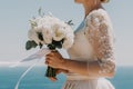 bride is holding a bouquet of white flowers. The bouquet is large and has a lot of flowers in it. The woman is wearing a Royalty Free Stock Photo