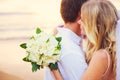 Bride holding bouquet of white flowers gazing at the ocean into Royalty Free Stock Photo