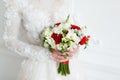 Bride holding bridal bouquet close up. red and white roses, freesia, brunia decorated in composition Royalty Free Stock Photo