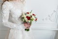 Bride holding bridal bouquet close up. red and white roses, freesia, brunia decorated in composition Royalty Free Stock Photo