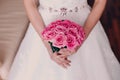 Bride holding bright wedding bouquet of pink roses closeup