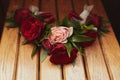 The bride holding in hand close-up the groom`s buttonhole flowers with white roses, and green and greenery Royalty Free Stock Photo